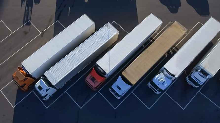 Deze afbeelding toont vrachtwagens die op een parkeerplaats staan opgesteld.